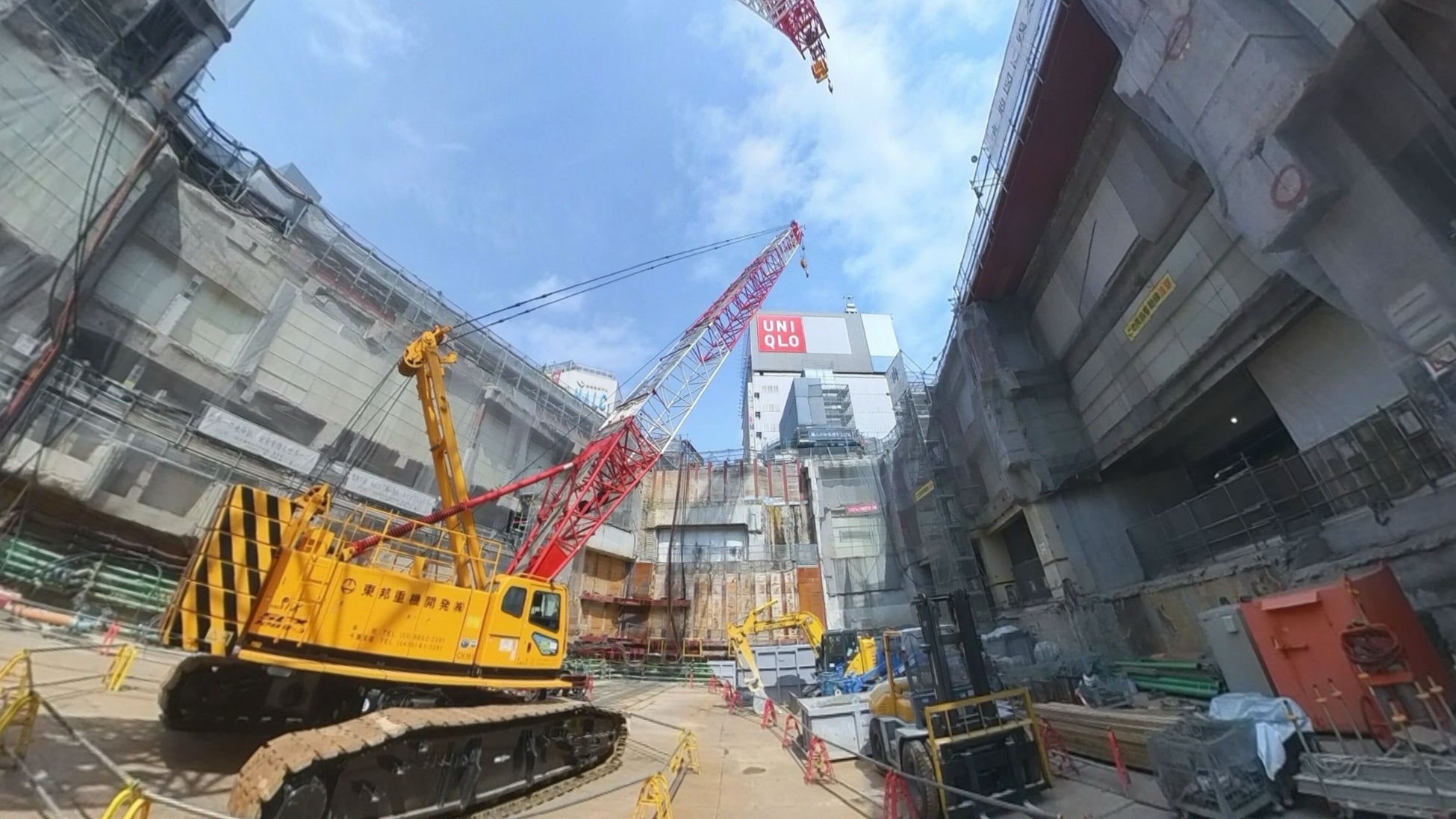 工事現場の地下部分から空を見上げたVR場面のイメージ。クレーンと周囲の構造物。