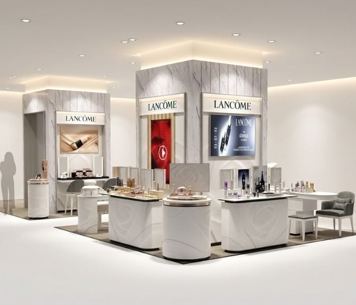 白を基調にした化粧品カウンター、商品展示、椅子、LANCOMEの表示がある売場の提供画像。